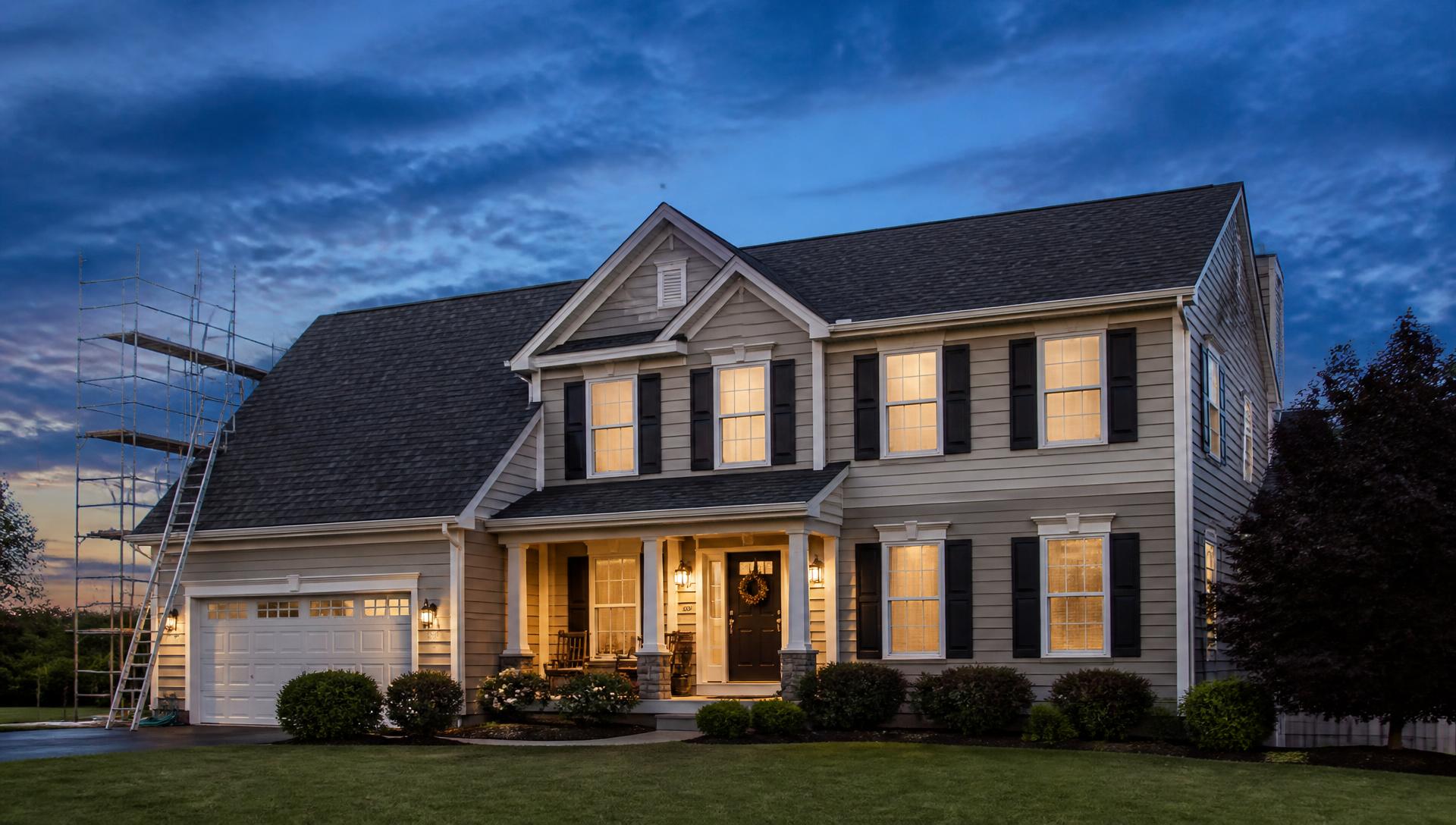 Home exterior with a new architectural shingle roof, siding and gutters at dusk